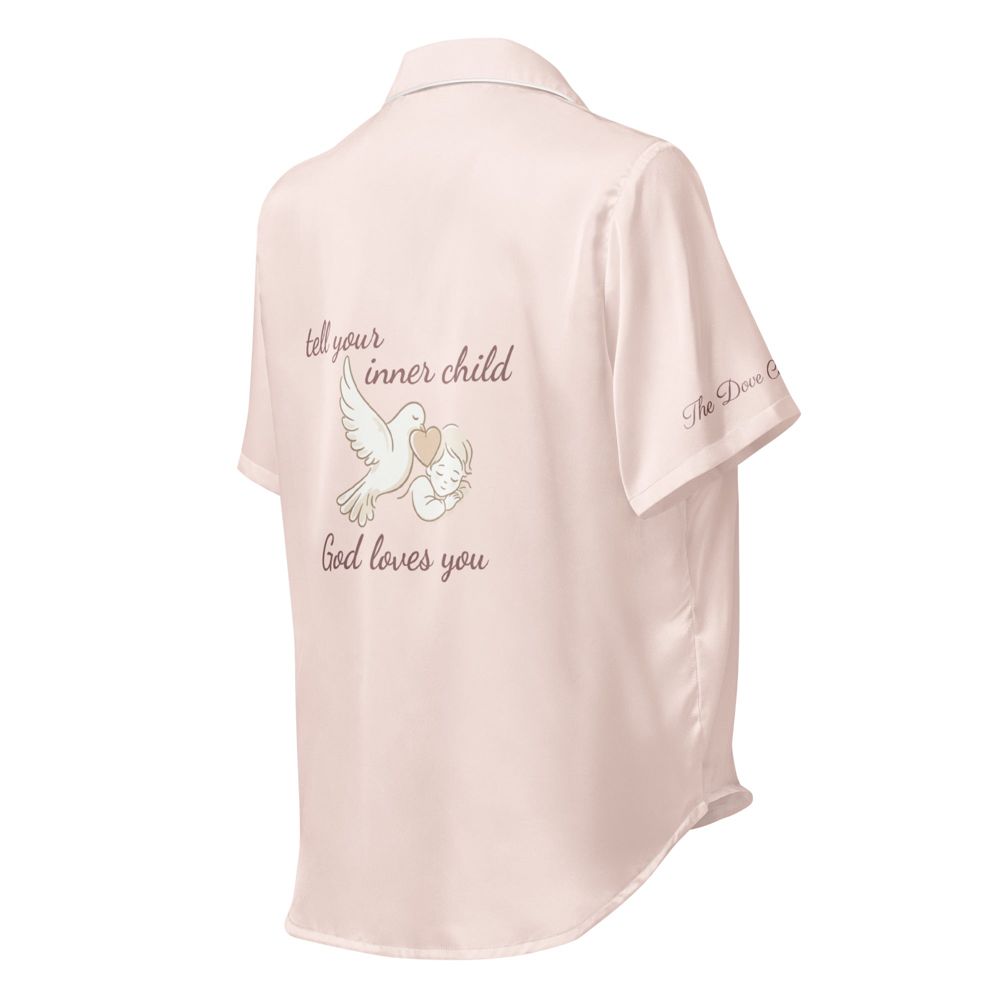 Pink silk pajama shirt with text that reads "tell your inner child God loves you" and dove graphic on a white background