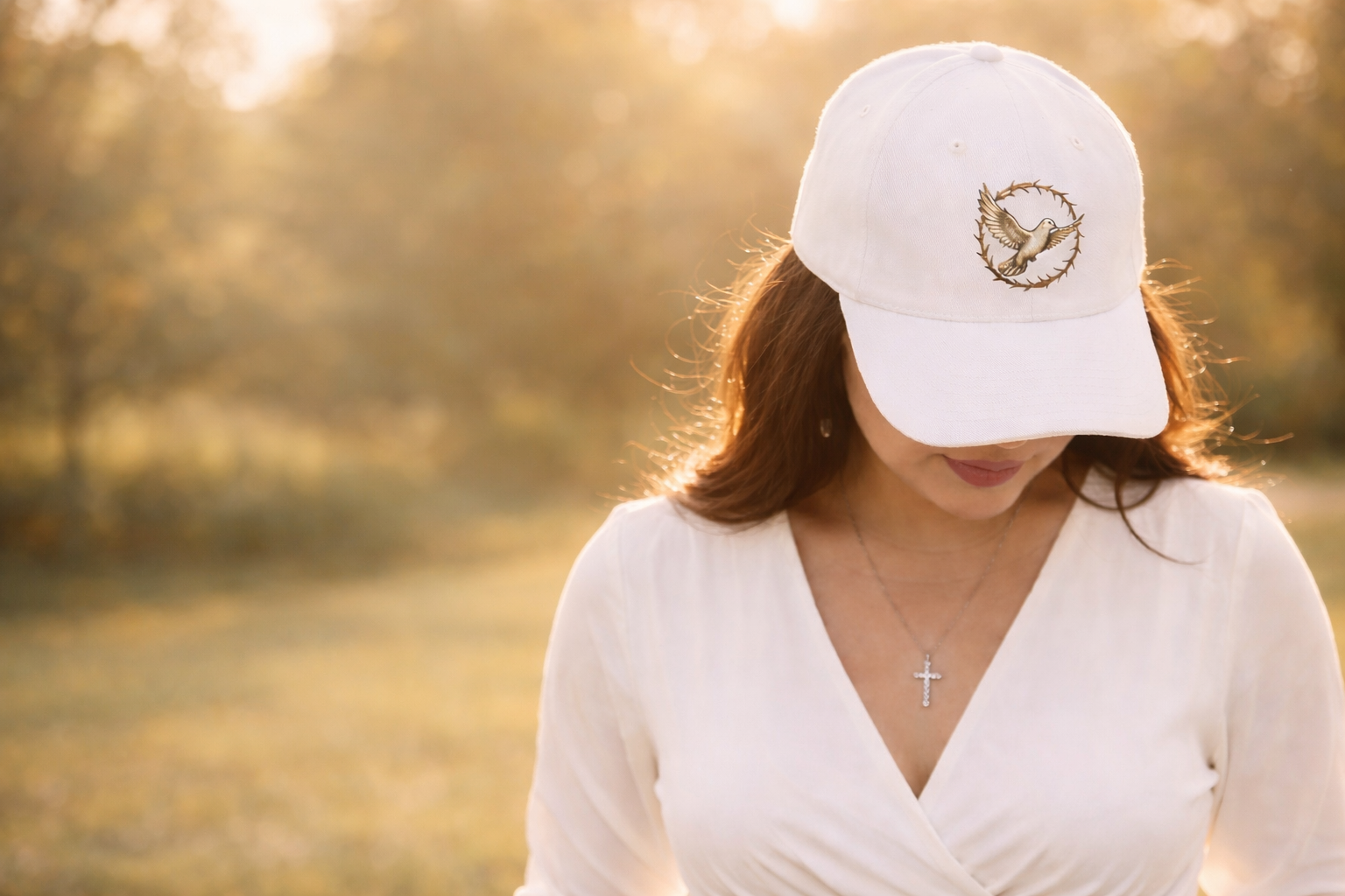 Woman wearing a white cap with a logo in a blurred outdoor setting